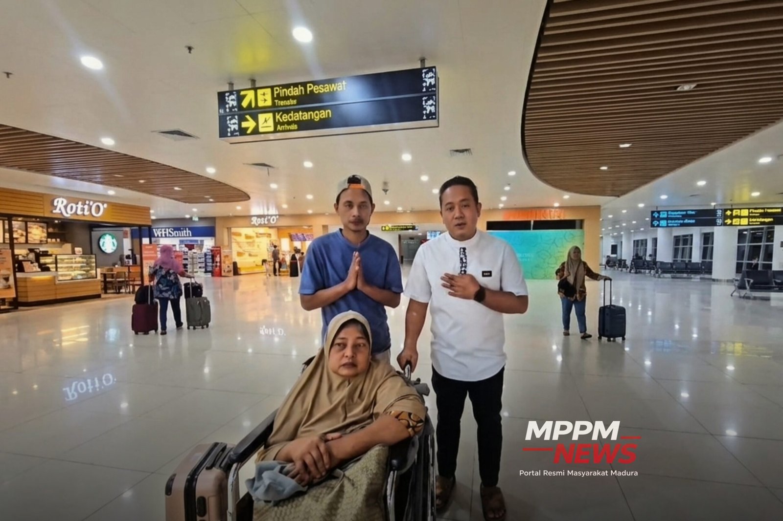 Fatmawati, PMI asal Sampang, duduk di kursi roda di Bandara Juanda Surabaya setelah dipulangkan dari Malaysia. Di belakangnya berdiri putranya Faisol dan Aipda Eko Purwanto.